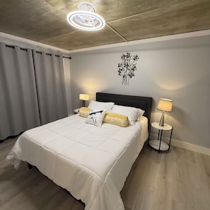 A hotel room with a bed, two bedside lamps, a wall decoration, and a ceiling light fixture. - Beautiful Condo In The Heart Of Olde Naples! (Naples)