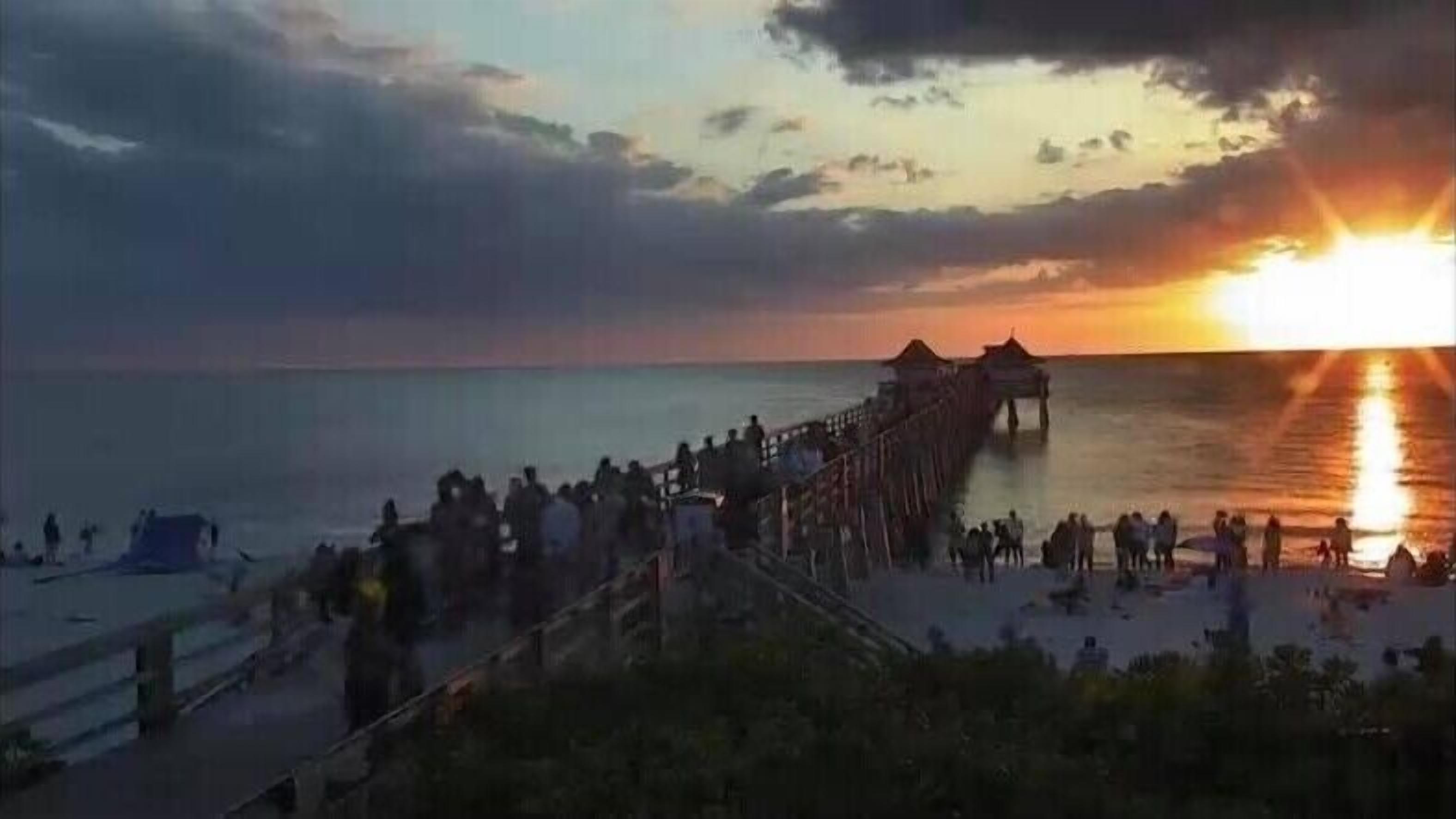 A pier extending into the water with people gathered at the end.