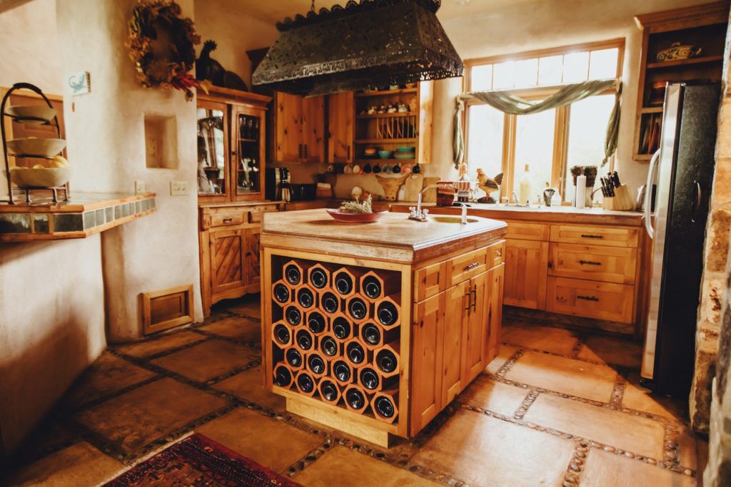 A rustic kitchen with wooden cabinets, a wine rack, and a large window.