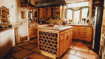 A rustic kitchen with wooden cabinets, a wine rack, and a large window.