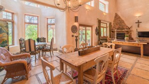 Un coin repas rustique avec une table et des chaises en bois, un lustre et une cheminée en pierre.