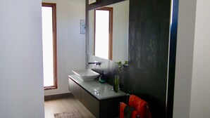 Un bagno moderno con un ampio specchio, un lavandino e un asciugamano rosso appeso a un portasciuga.