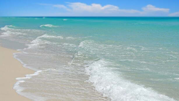 Una playa con aguas turquesas cristalinas y olas suaves.