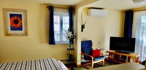 Une chambre d’hôtel avec un lit, une télévision, une chaise et une fenêtre avec des rideaux.