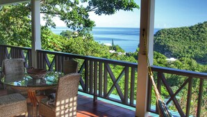 A balcony with wicker furniture, a glass table, and a view of the sea and forest. - Spectacular views overlooking Marigot Bay (Marigot Bay)