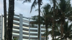 A multi-story building with a modern design, surrounded by palm trees and greenery. - Renovated building, 170m2, 4 bedrooms - air conditioning, terrace and barbecue, beachfront. (Bertioga)