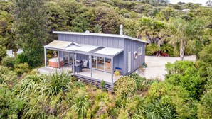 A modern house with a glass-enclosed porch, a hot tub, and a deck.