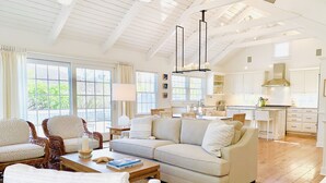 A spacious living room with a large sofa, two armchairs, a coffee table, and a dining area with a table and chairs. - Upscale Beach House Brant Point (Nantucket)