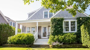 A two-story house with a covered porch, stone steps, and a well-maintained lawn. - Upscale Beach House Brant Point (Nantucket)