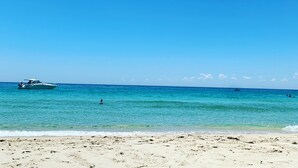 A beach with a clear blue sky, a boat in the water, and a sandy shore. - Beachside 880  beachfront luxury Apartment with Sunset views from the balcony. (Busselton)