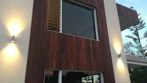 A modern building with a wooden facade, large windows, and exterior lighting. - Beachside 880  beachfront luxury Apartment with Sunset views from the balcony. (Busselton)