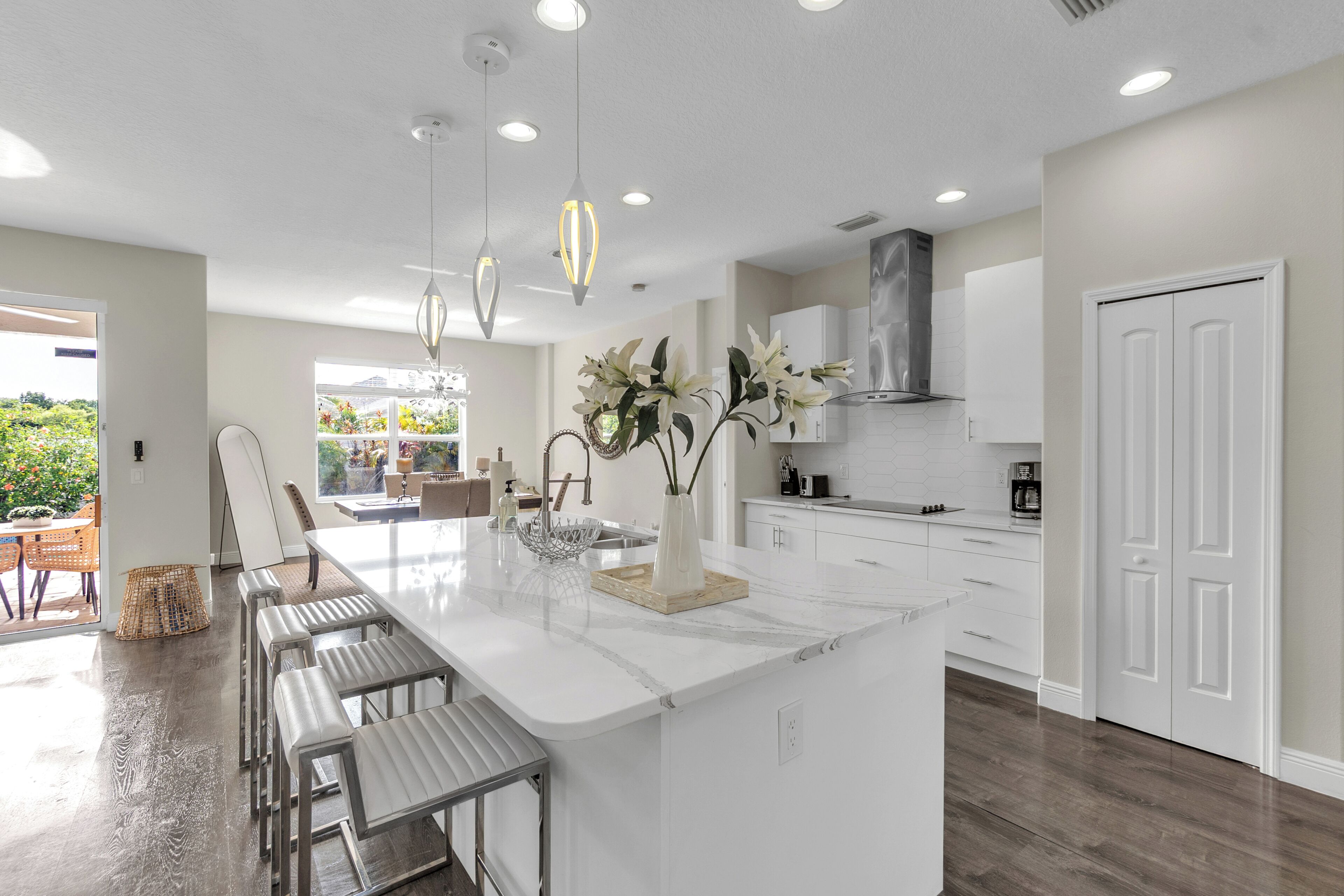 A modern kitchen with a large island, white cabinetry, and pendant lighting.