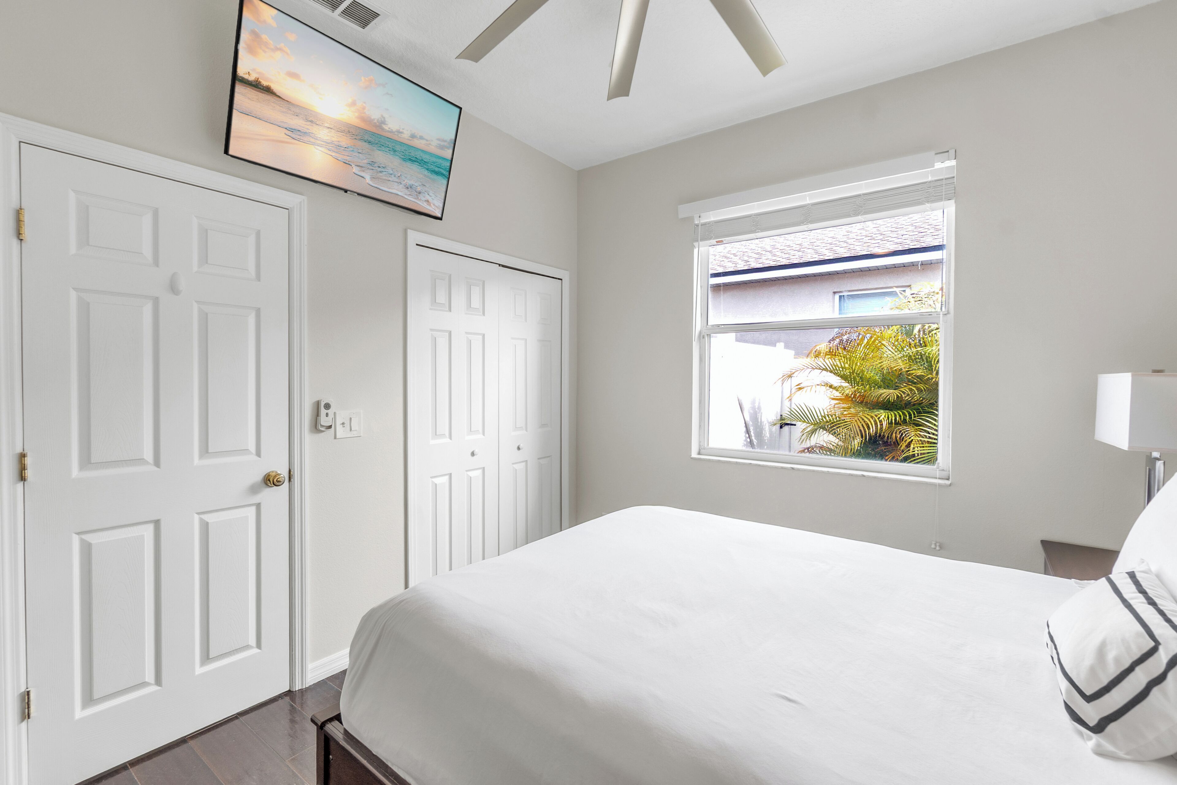 A bedroom with a bed, a window with a view, and a TV mounted on the wall.