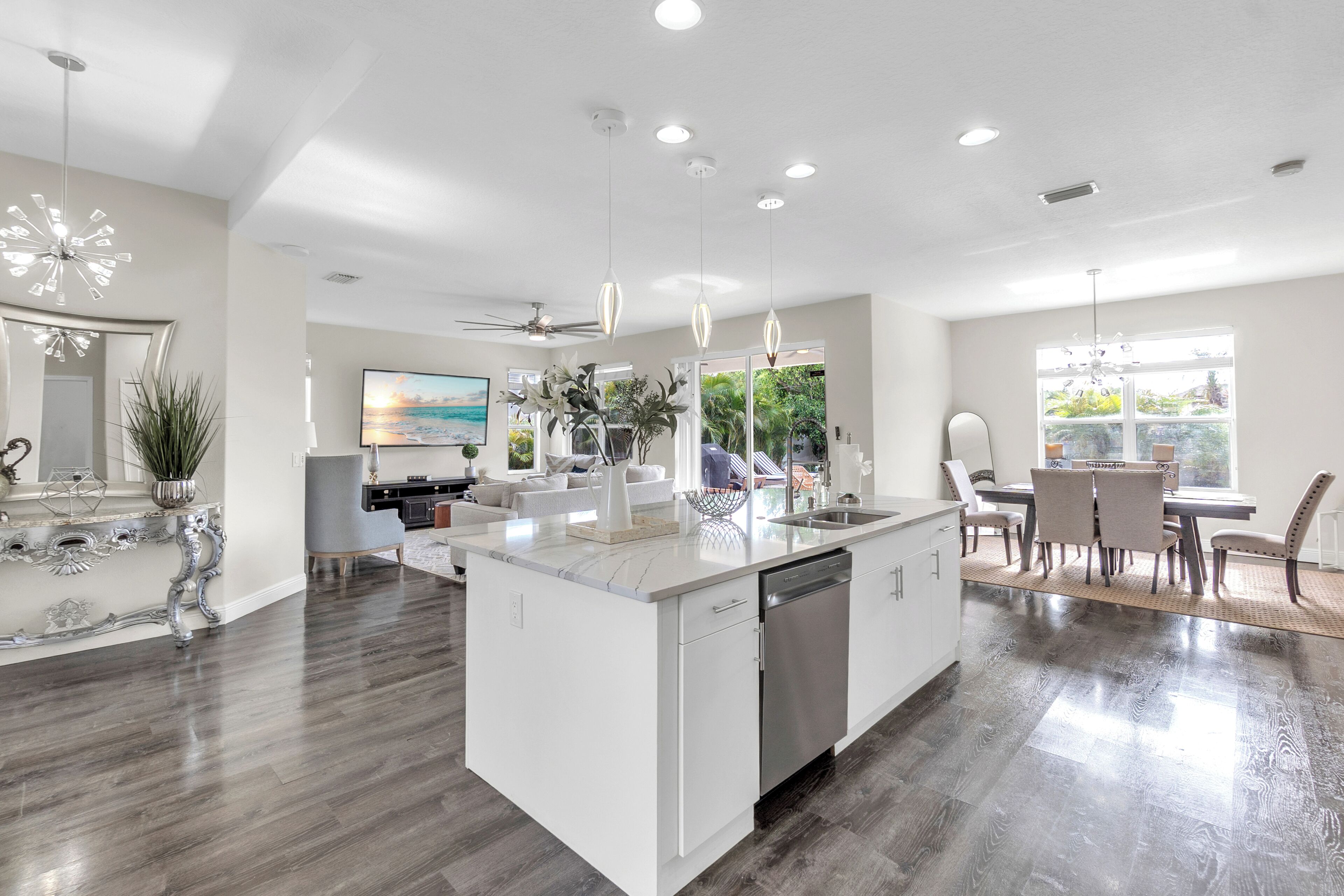 A modern kitchen with a central island, white cabinetry, and a dining area with a table and chairs.