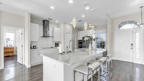 A modern kitchen with a large island, white cabinetry, stainless steel appliances, and pendant lighting. - Paradise Pool Heated Home Near Siesta Key & IMG Academy (Bradenton)