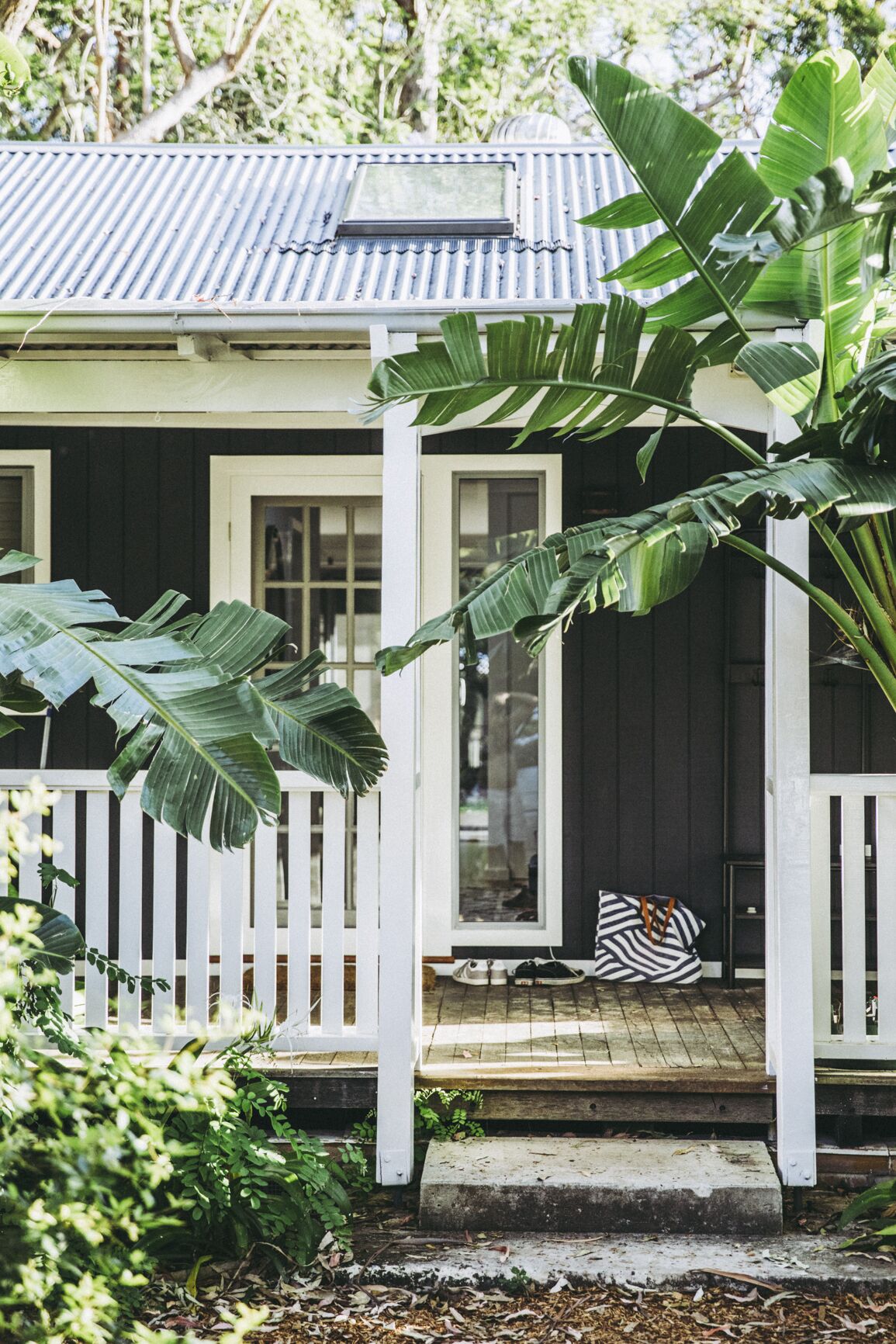 A house with a porch, a sliding glass door, and a small outdoor seating area with a striped cushion.