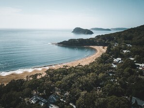 Una zona costera con playa, una pequeña isla y bosque denso.
