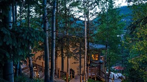 Eine Holzhütte mit einer Terrasse, umgeben von Bäumen und einem Berg im Hintergrund.