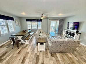 A spacious living area with a dining table, sofa, and TV.