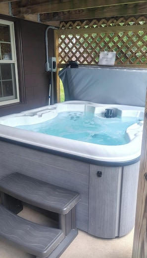 Un jacuzzi con escalones, una cerca de madera y un cuadro de empalmes.