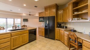 Una cocina con armarios de madera, un refrigerador negro, un microondas y un lavavajillas.