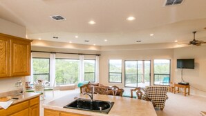 Una cocina amplia con armarios de madera, una isla central con un fregadero y un comedor con mesa y sillas.