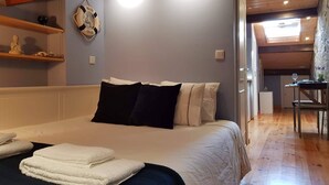 Ein Schlafzimmer mit einem großen Bett, einem kleinen Schreibtisch mit Stuhl, einer Wandleuchte und einem Regal mit Dekoration.