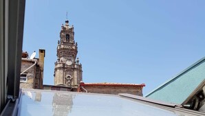Blick auf einen Glockenturm durch ein Fenster, mit blauem Himmel im Hintergrund.