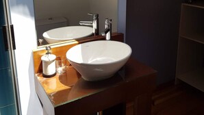 Ein Badezimmer mit Waschtisch aus Holz, zwei Waschbecken und einem Spiegel.