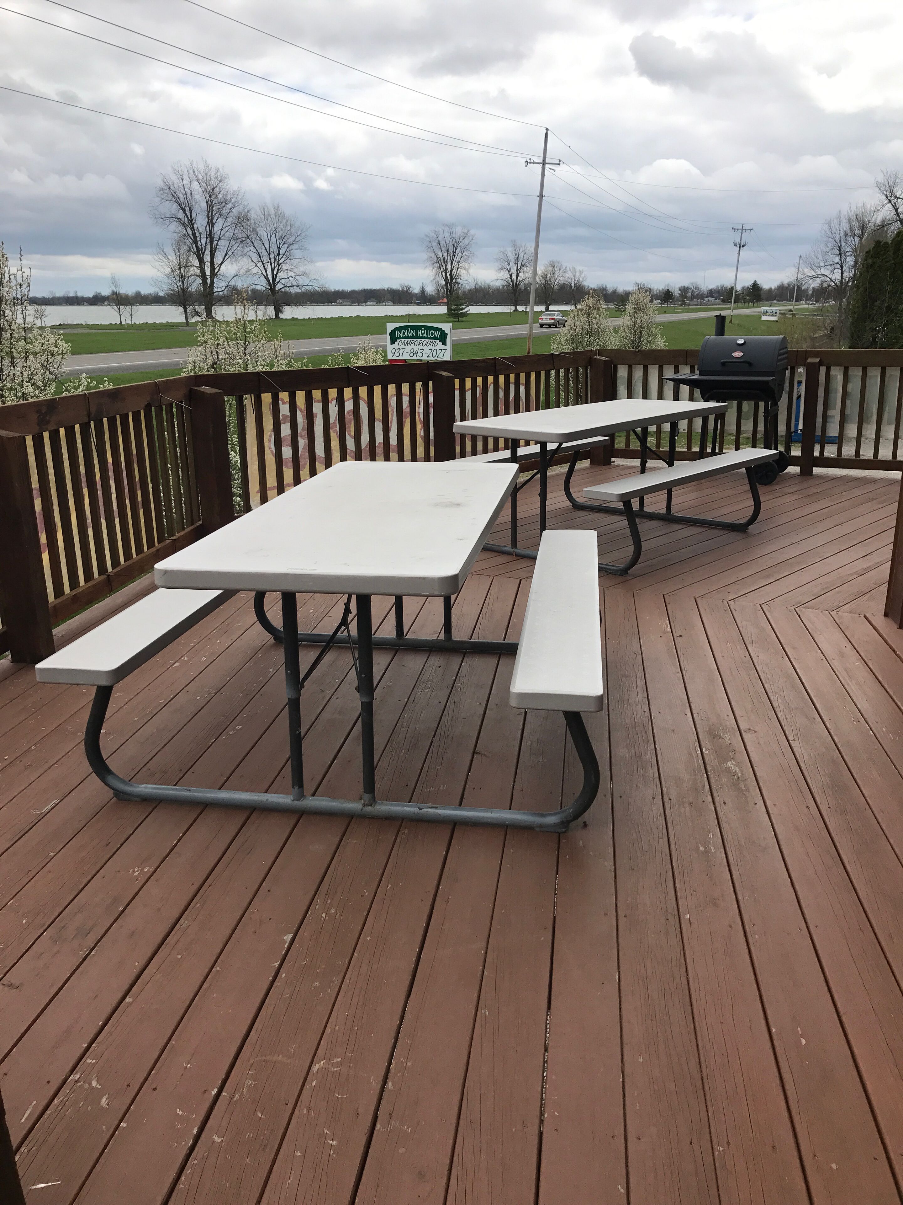 Une terrasse en bois avec des tables de pique-nique et un barbecue.