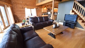 Un salon spacieux avec un grand canapé en cuir, une table basse en bois et un téléviseur.