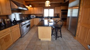 A spacious kitchen with wooden cabinets, stainless steel appliances, and a central island with bar stools.