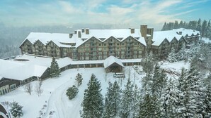 Un grand chalet comprenant plusieurs bâtiments, un paysage enneigé et une piste de ski.