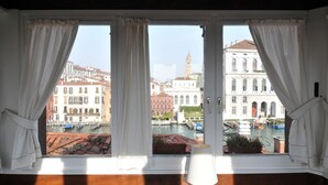 A room with a large window offering a view of Venice's historic buildings and canals.
