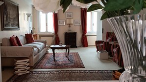 A living room with a sofa, a coffee table, a rug, and a vase with flowers.