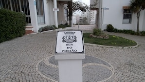 A cobblestone courtyard with a sign reading "Rua do Portão" and a building in the background.