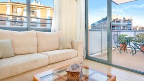 Un salón con sofá, una mesa de centro de vidrio y vistas de la ciudad a través de amplios ventanales.