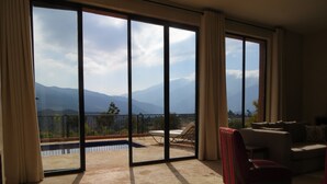 Un balcón amplio con piscina, un sofá y una silla roja.