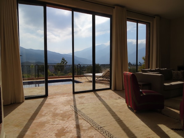 A spacious balcony with a pool, a sofa, and a red chair.