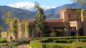 Un edificio con jardín y una montaña al fondo.