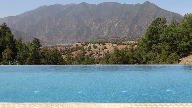 Una piscina azul cristalina con montañas al fondo.