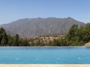 A clear blue swimming pool with a mountain backdrop.