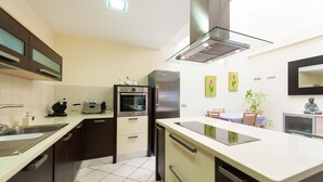 Eine moderne Küche mit Einbauofen, Kühlschrank und einer Essecke mit Tisch und Stühlen.