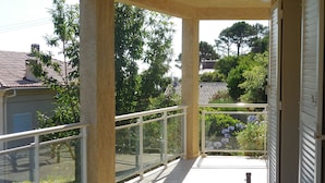 A balcony with a glass railing, a tiled floor, and a view of surrounding buildings and trees. - Discover the originality of CAP (P.M.R. access)7 pers (Sisco)