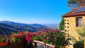 Un edificio in pietra con tetto a tegole e vista sulle montagne.
