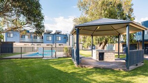 A residential area with a swimming pool, a covered outdoor seating area, and a fenced yard. - Penguins by the Beach - sleeps 9 (COWES)