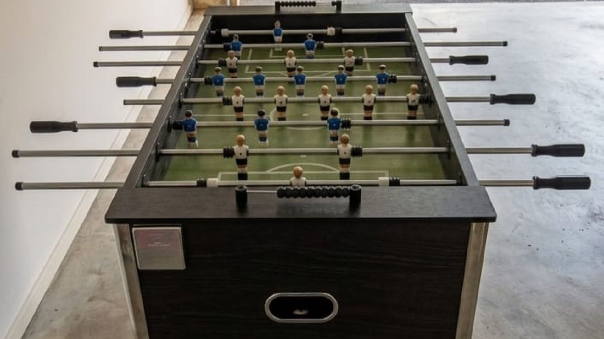 A foosball table with multiple rods and figures, a control panel with buttons, and a power outlet.