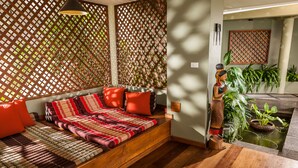 A room with a wooden bench, red cushions, and a decorative wall with lattice patterns.