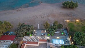 An aerial view of a beachside property with a swimming pool, patio seating, and a small garden area. - Villa Perla with Sea View (rhodes)