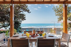 A wooden table set for breakfast with a view of the ocean.